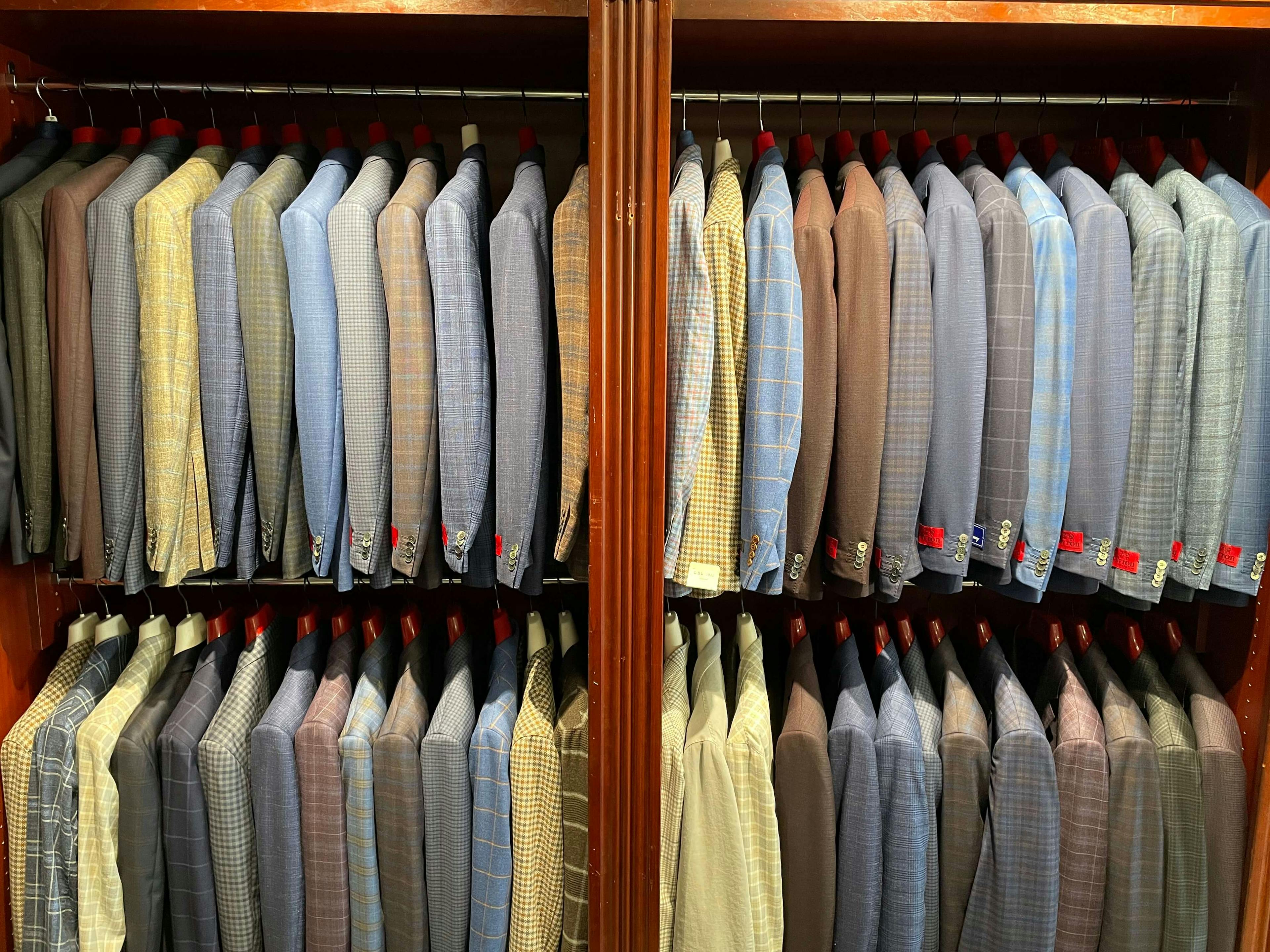 Suits and sports coats display on clothing rack in JwR's store.